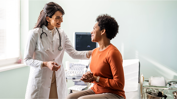Woman in orange shirt talking to female healthcare provider