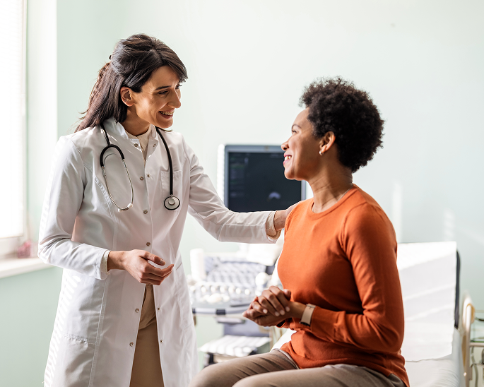 Woman in orange shirt talking to female healthcare provider