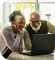Man and woman looking down at a laptop in the kitchen