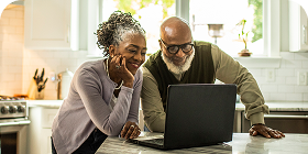 Man and woman looking down at a laptop in the kitchen