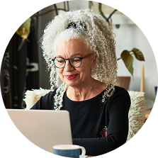 Woman in glasses looking down at a laptop